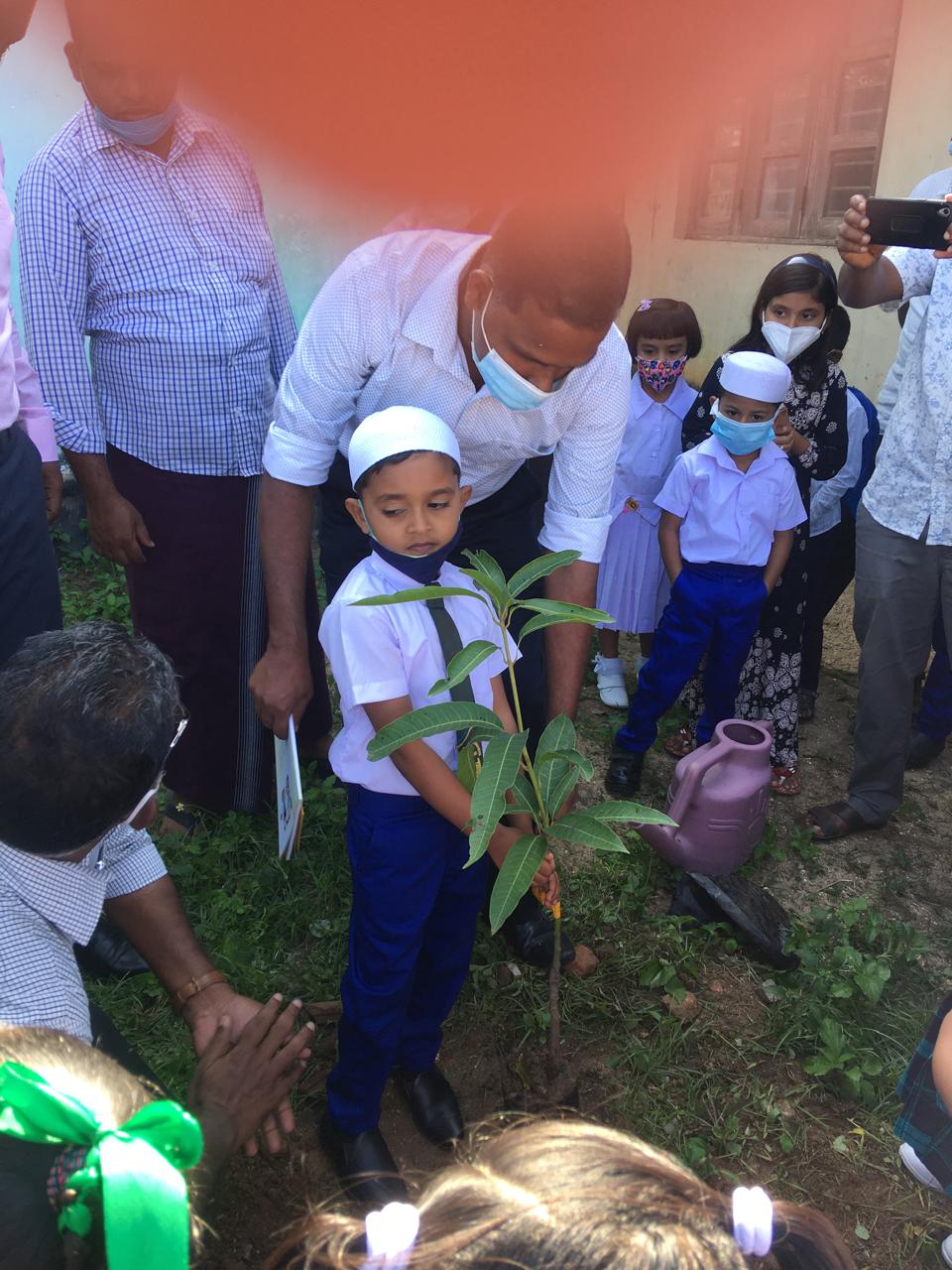 Young participant watering a newly planted tree during a community activity in Pottuvil.